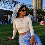 Festival-goer in a white tee and gingham trousers wearing the Dottie Medium Square Scarf in sky blue as a hand-painted floral headscarf